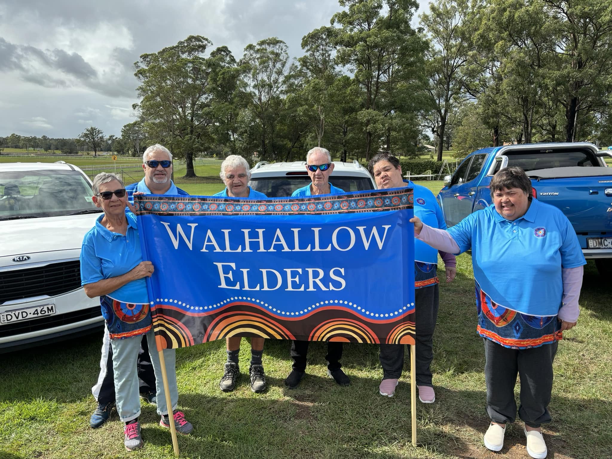 Walhallow Elders holding their banner outdoors on a grassy field